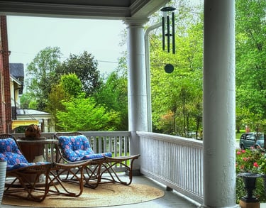 Front porch with lounger chairs and wind chimes 2123 Rivermont apartments