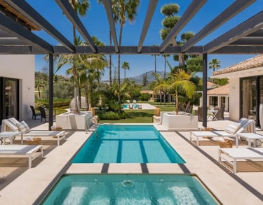 Guest heated pool surrounded by terraces and palm gardens at Villa El Olivo, Marbella