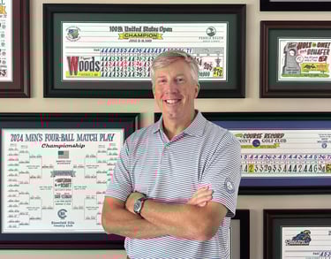 Casey standing in front of a wall of his colorful golf artwork.