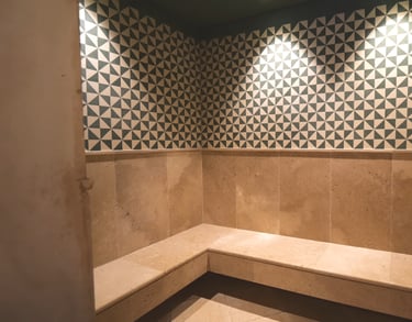 Steam room at Villa La Gratitud’s with geometric tile design and built-in stone bench.