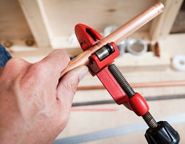 man cutting copper pipe