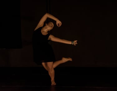 a woman in a black dress is dancing on stage