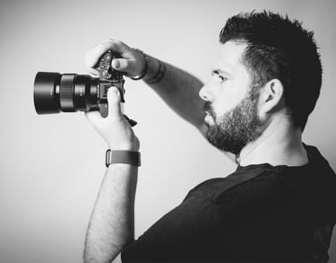 Portrait en noir et blanc de Cyril Steau, photographe à Paris, en pleine prise de vue avec un appareil photo professionnel.