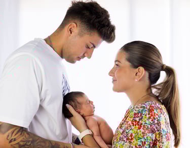 Sessió de fotos newborn a Girona amb una bebè dormint als braços dels pares en estudi fotogràfic