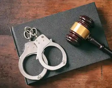 Esposas metálicas sobre un libro y mazo judicial, vista en primer plano.