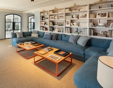 TV lounge at Villa La Gratitud with blue sectional sofa, wall of bookshelves, and large windows. 