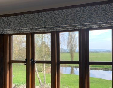 A roman blind in a leafy fabric designed to work with the view of open fields