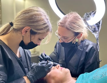 Darina y su estudiante haciendo cejas para una clienta