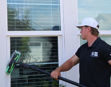 a young man cleaning a window with a waterfed pole