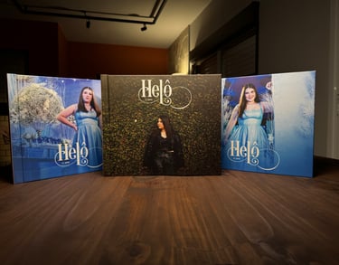 Três álbuns fotográficos de 15 anos com capas personalizadas expostos sobre mesa de madeira.