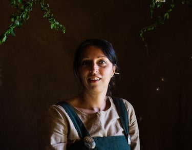 an atmospheric picture of a woman in green viking clothes surrounded by herbal plants
