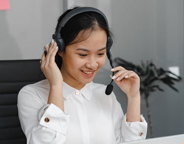 a woman in a white shirt and headphones on a laptop