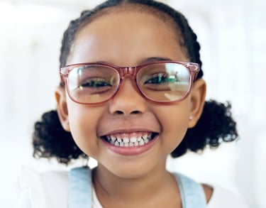 Little girl smiling and wearing a kid's glasses