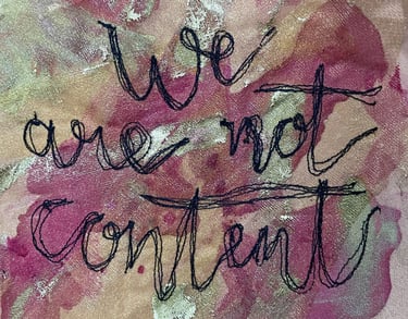 machine embroidered text which says 'we are not content' in cursive writing on a pink background