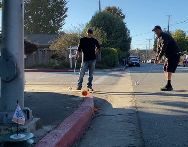Street golf chip shot: two men aim for the urban capture hole