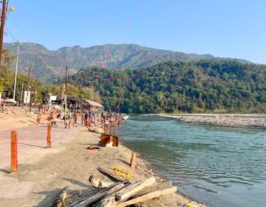 View of the sacred Ganges River flowing through Rishikesh, India, with the Himalayan mountains in the background.