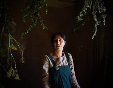 an atmospheric picture of a woman in green viking clothes surrounded by herbal plants
