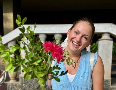 Alena Booth smiling next to red flowers in india