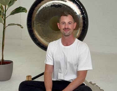 a man sitting in front of a gong in a calming space