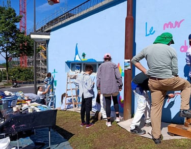 Gruppo di bambini e adulti dipinge insieme su muro azzurro durante laboratorio artistico Poliops.