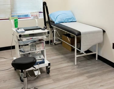 Neurology exam room with examination table and diagnostic equipment for neurological evaluations.