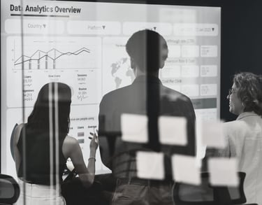 a group of people standing in front of a white board looking at slide titled Data Analytics Overview