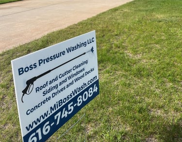 Boss Pressure Washing LLC yard sign in front of a freshly cleaned driveway and home.