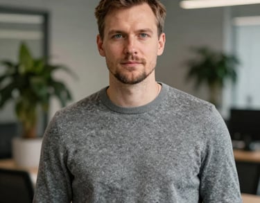 Professional portrait of a man in a grey sweater, modern office environment with blurred plants in the background, Northern European / Baltic / Estonian.