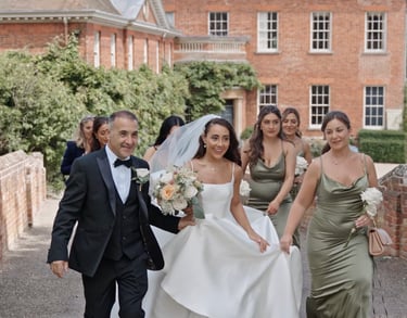 bride and father along with bridesmaids walking towards the the ceremony