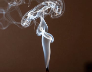 Photography of soft incense smoke curling in the air in a dark room, backlit by a saffron light. Mystical and serene atmosphere in a South Asian setting.
