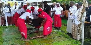 Porteurs en tenue rouge traditionnelle avec un cercueil lors de funérailles à Douala Deido