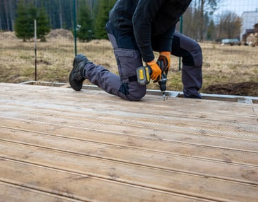 handyman drilling and building an outdoor wooden deck at an Auckland property