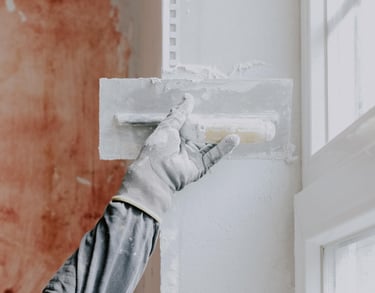 handyman applying plaster to repair an interior wall in an Auckland home