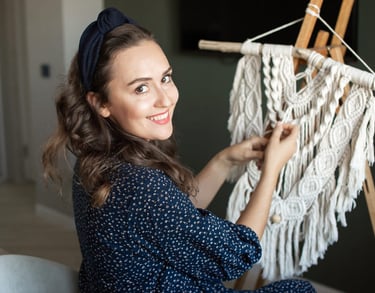 Una mujer sonriente creando un tapiz blanco de macramé hecho a mano