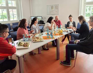 Diverse colleagues sharing lunch and snacks at a business meeting table in an office.