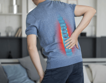 A man holding his lower back with a glowing 3D spine graphic representing chronic back pain and injury.