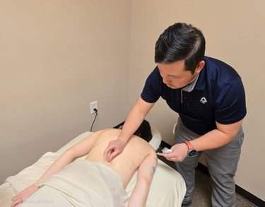 Dr. Xiong performing acupuncture with fine needles placed in patient’s back for pain relief therapy.