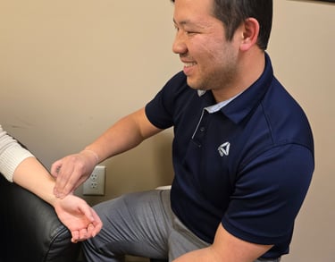 Dr. Xiong performing wrist pulse check during acupuncture health assessment in clinical setting