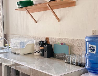 Organized kitchen countertop with dish drying rack, knife block, and blue water dispenser tank.