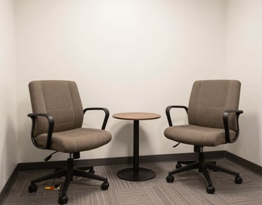 A clean, bright photograph of a modern North American consultation room with two comfortable chairs and a small table, designed to feel safe and private.