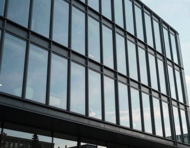 An architectural photograph of a modern Danish office building with large glass facades, reflecting a pale sky blue, symbolizing transparency and progress in a professional context.