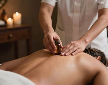 Action shot of a therapist's hands applying essential oil onto a guest's back in a dimly lit, luxury South Asian spa room.