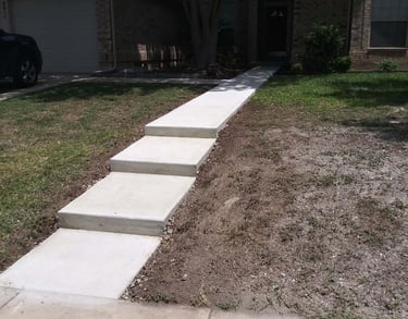 a concrete walkway with steps leading up to a house