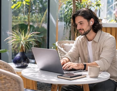 a man sitting at a table with a laptop and a cup of coffee