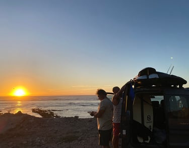 a man standing next to a car with a surfboard on it