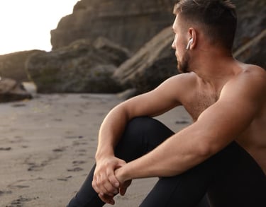 a sugar baby sitting on a beach with a cell phone in his hand