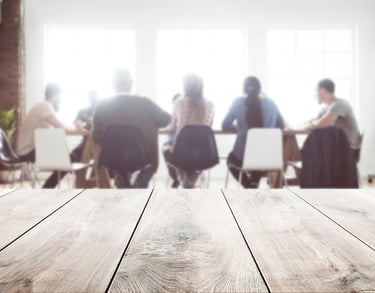 blurry picture of a table with a team discussing and lsitening