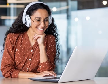 Young woman with headset smiling at laptop