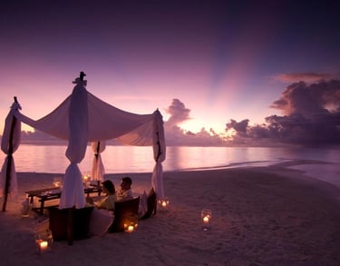 a couple sitting on a beach at sunset
