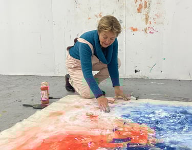 Artiste peintre travaillant une toile au sol dans son atelier